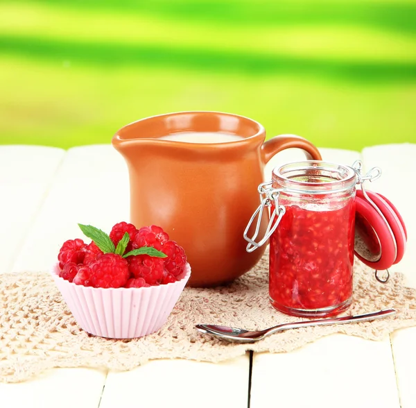 Fresh raspberry, raspberry jam and cream in jug on wooden table, on bright background — Stock Photo, Image