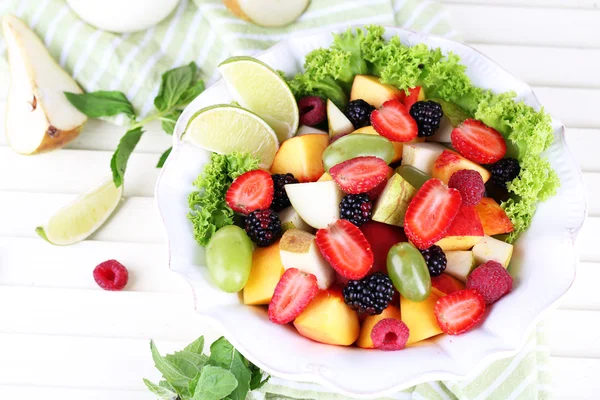 Ahşap masa üzerinde plaka içinde meyve salatası — Stok fotoğraf