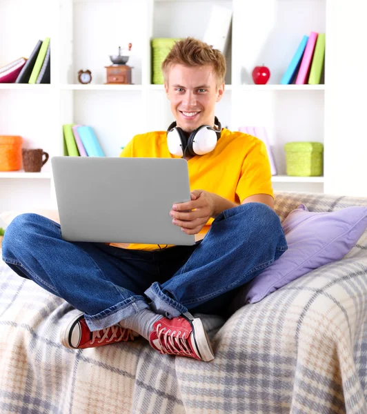 Mladý muž relaxační na pohovce s notebookem — Stock fotografie