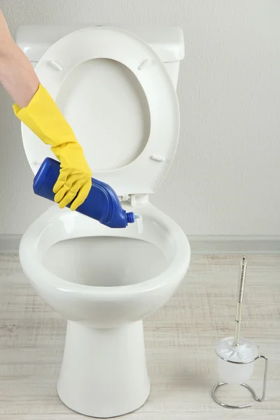 Woman hand with spray bottle cleaning a toilet bowl in a bathroom Stock Photo