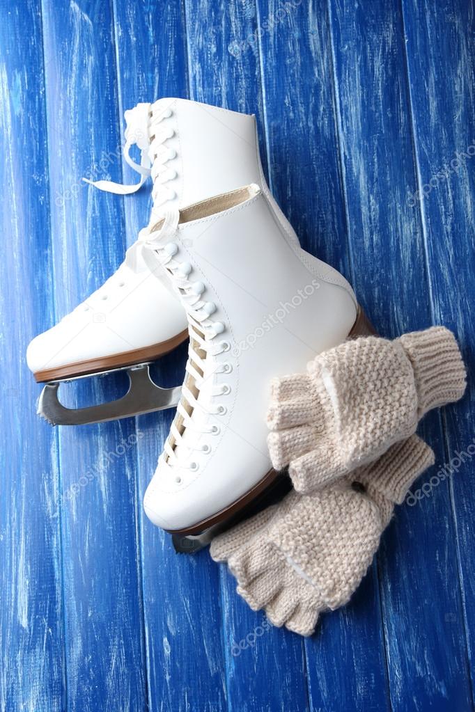 Wool fingerless gloves and skates for figure skating, on wooden background