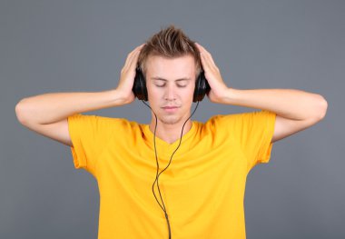 yakışıklı genç adam gri arka planda müzik dinlemek