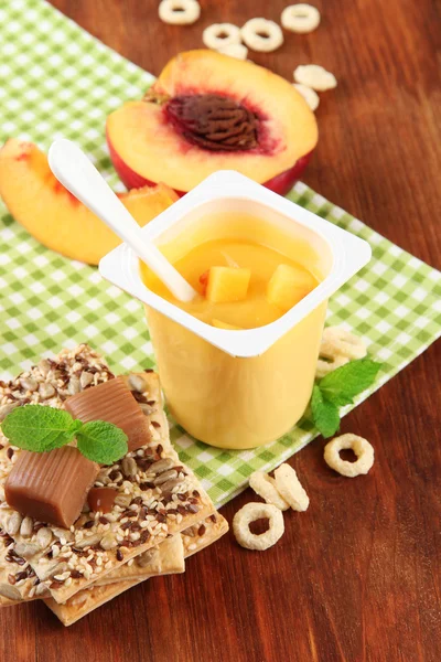 Yogurt saporito con pezzi di frutta fresca, biscotti e fiocchi, su sfondo di legno — Foto Stock
