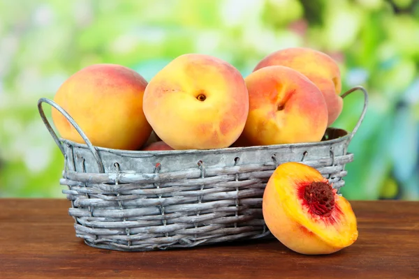 Спелые сладкие персики в плетеной корзине, на ярком фоне — стоковое фото