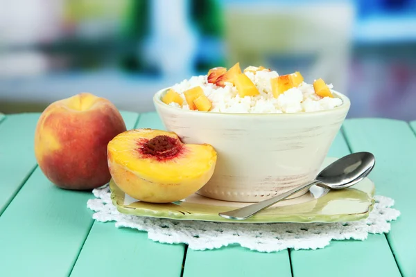 Sour cheese and pieces of fresh peach,on wooden table, on bright background — Stock Photo, Image