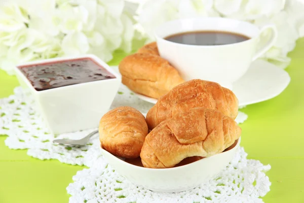 Leckere Croissants und eine Tasse Kaffee auf dem Tisch aus nächster Nähe — Stockfoto