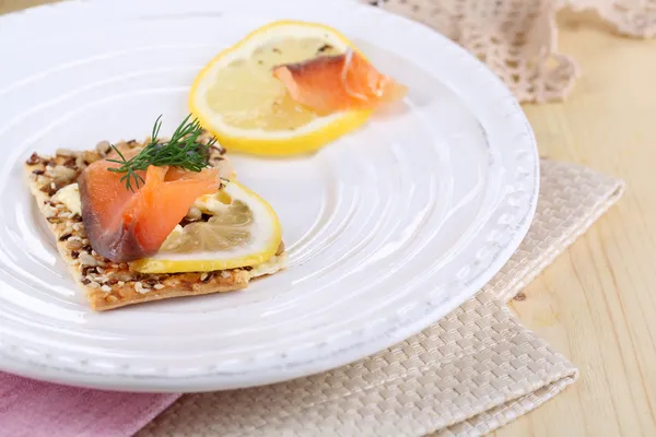 Salmon sandwich on plate on wooden table close-up — Stock Photo, Image