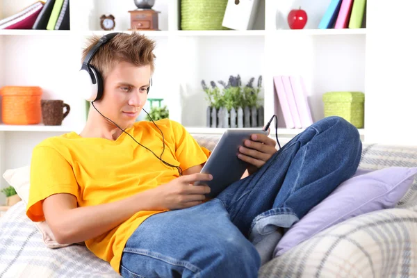 Hombre joven relajándose en el sofá con la tableta — Foto de Stock