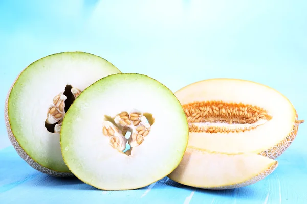 Melones maduros sobre mesa de madera sobre fondo azul —  Fotos de Stock