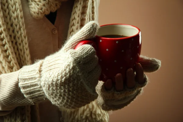 Mãos femininas com bebida quente, no fundo de cor — Fotografia de Stock