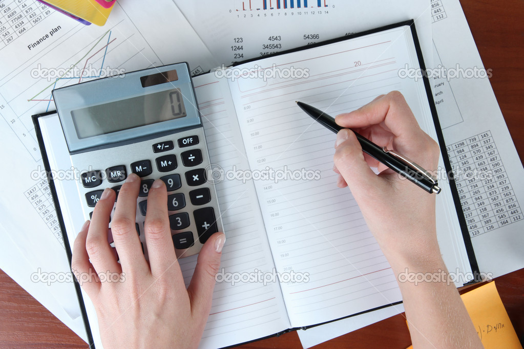 Woman hands counting on calculator on worktable background