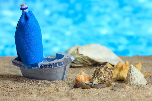 Bateau jouet bleu sur sable, sur fond bleu — Photo