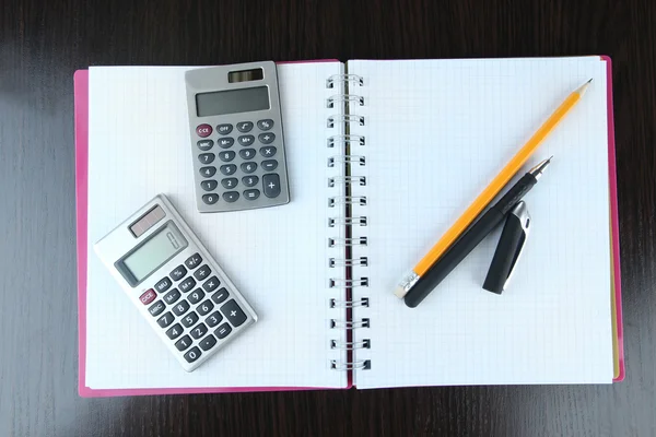 Блокнот з ручкою, олівцем та калькуляторами на дерев'яному фоні — стокове фото