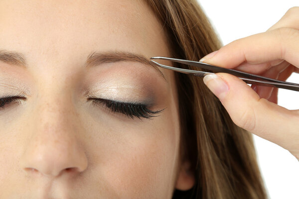 Young woman having eye-brows plucked isolated on white