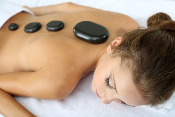 Beautiful young woman having stone massage in spa salon — Stock Photo, Image