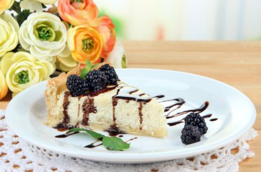 dilim peynirli kek çikolata sosu ve plaka, parlak zemin üzerine ahşap masa üzerinde blackberry