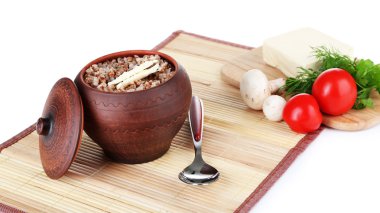 Buckwheat in pot with butter and vegetables isolated on white