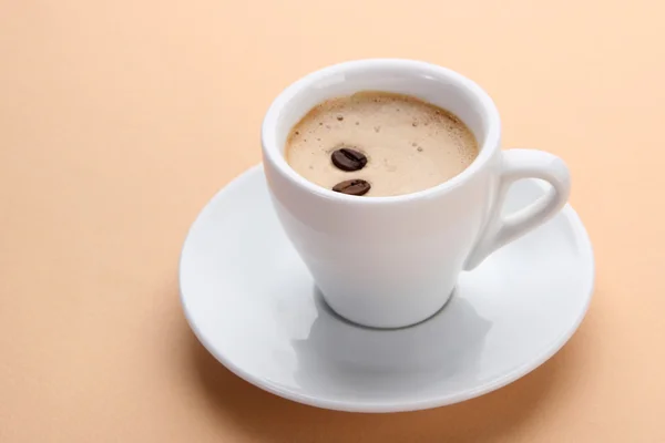 Xícara de café com grãos de café em fundo bege — Fotografia de Stock