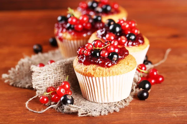 Leckere Muffins mit Beeren auf Holztisch — Stockfoto