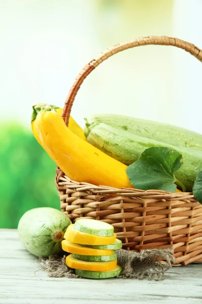 Gesneden en hele rauwe courgette in rieten mand, buitenshuis — Stockfoto