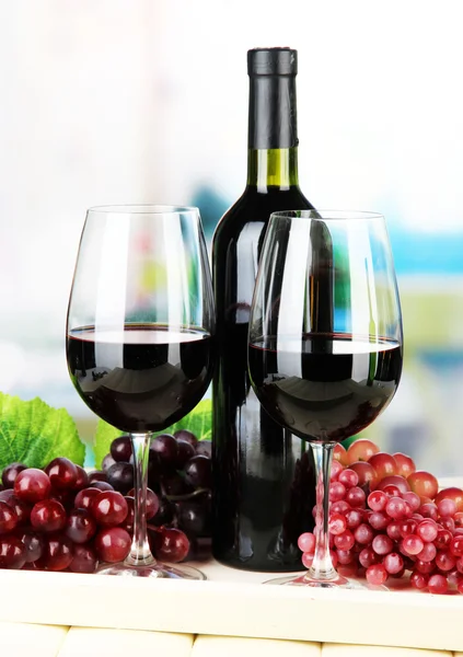 Rijpe druiven, fles en glazen wijn op het dienblad, op lichte achtergrond — Stockfoto