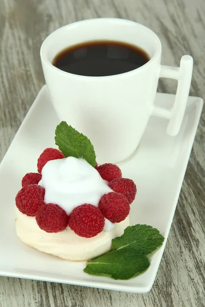 Gâteau meringue savoureux aux baies et tasse de café, sur table en bois — Photo