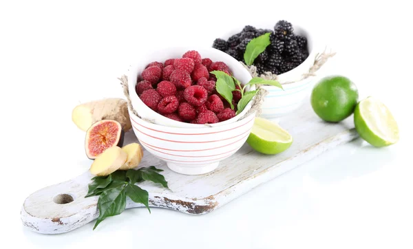 Framboises et mûres dans de petits bols à bord isolés sur blanc — Photo