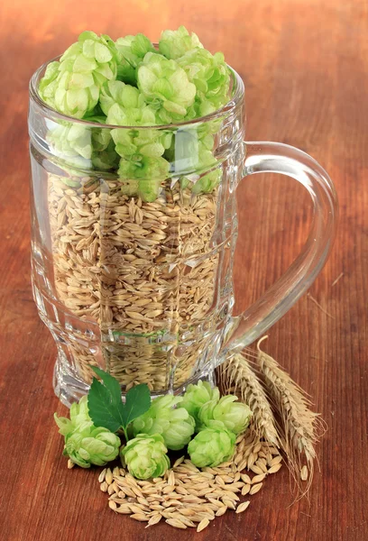 Glass of fresh green hops and barley, on wooden background — Stock Photo, Image