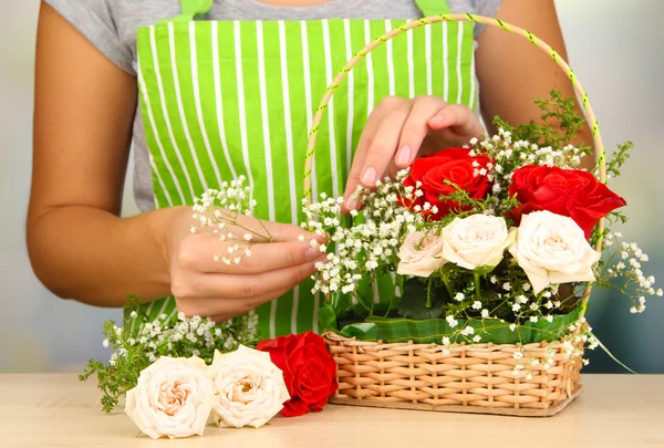 Florist makes flowers bouquet in wicker basket — Stock Photo, Image