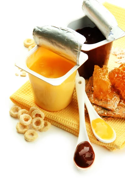 Tasty desserts in open plastic cups and honey combs, fruits, on napkin, isolated on white — Stock Photo, Image