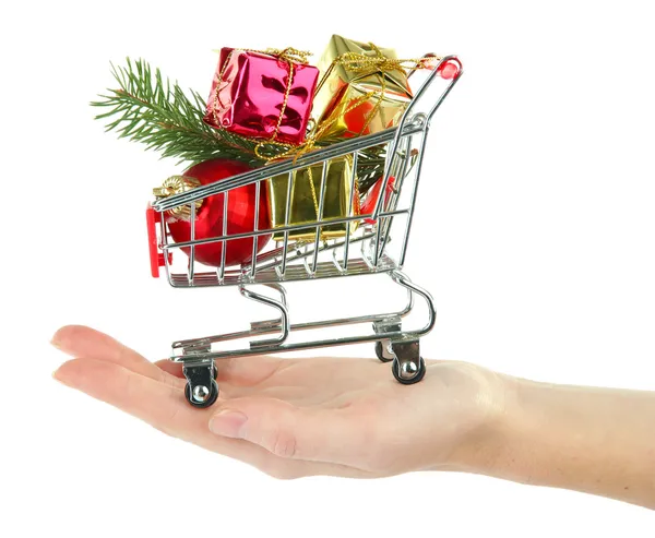 Mano sosteniendo regalos de Navidad en el carro de la compra, aislado en blanco — Foto de Stock