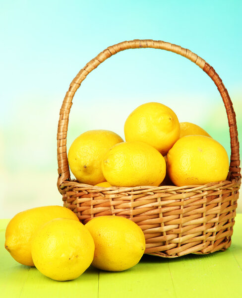 Ripe lemons in wicker basket on table on bright background