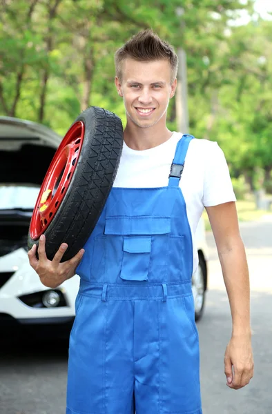 Auto mechanic with tire on his shoulder — Stock Photo, Image