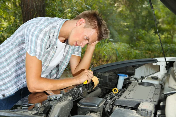 Молодой водитель ремонтирует двигатель автомобиля на открытом воздухе — стоковое фото