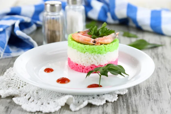 Gekleurde rijst op plaat in de buurt van servet op houten tafel — Stockfoto