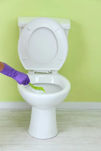 Woman hand with brush cleaning a toilet bowl in a bathroom — Stock Photo, Image