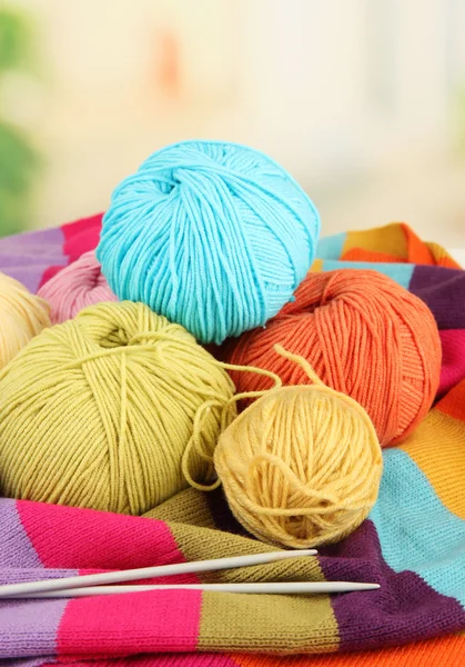 Multicolored clews with needles and bright scarf closeup — Stock Photo, Image