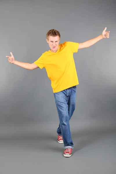 Knappe jongeman dansen op grijze achtergrond — Stockfoto