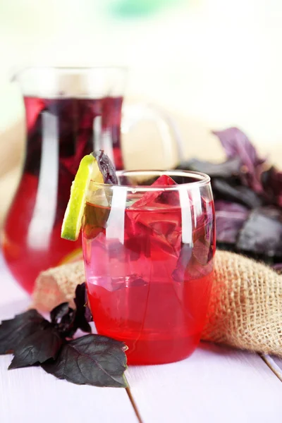 Rote Basilikumlimonade in Krug und Glas, auf Holztisch, auf hellem Hintergrund — Stockfoto