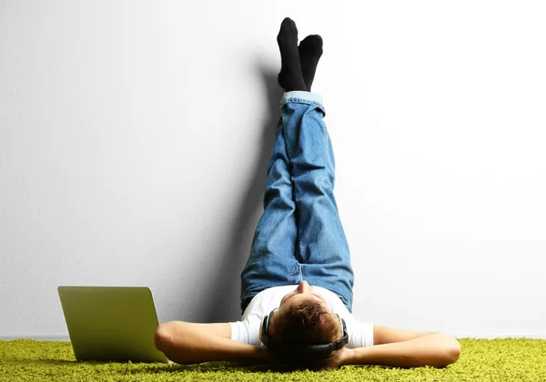 Młody człowiek, relaksując się na dywan i słuchania muzyki — Zdjęcie stockowe