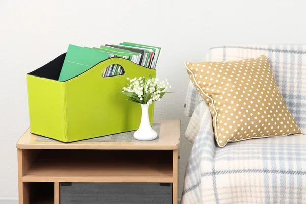 Журналы и папки в зеленой коробке на тумбочке в комнате — стоковое фото