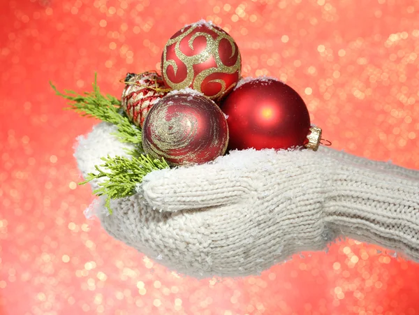 Kvinna händer i vantar julgran bollar, på färgbakgrund — Stockfoto