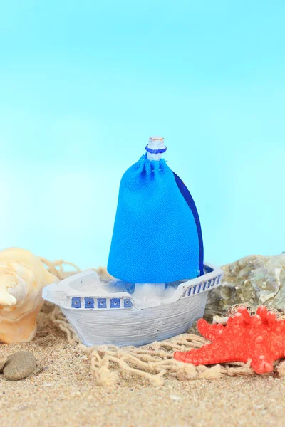 Bateau jouet bleu sur sable, sur fond bleu — Photo