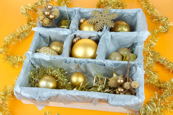 Vánoční hračky v dřevěné krabici na žlutém podkladu — Stock fotografie