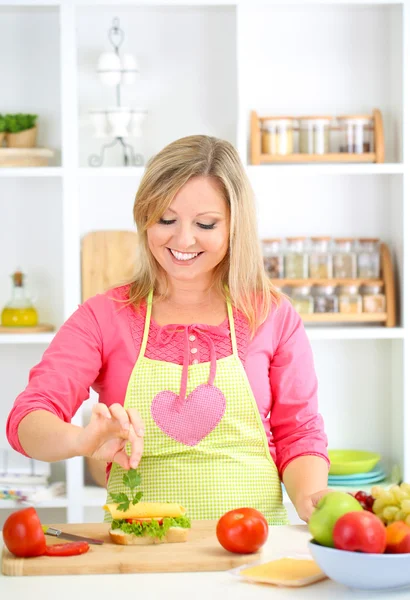 Happy smiling woman in kitchen preparing sandwich — Stock Photo, Image