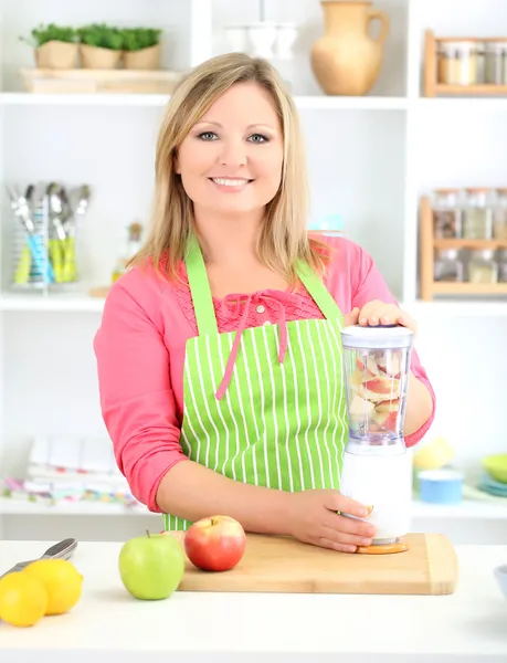 Boldog mosolygós nő a konyhában friss gyümölcskoktélt készít — Stock Fotó