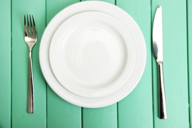 Plate and cutlery on wooden table close-up