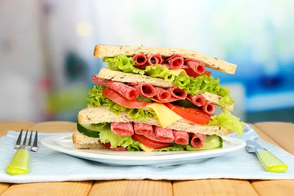 Huge sandwich on wooden table, on bright background — Stock Photo, Image