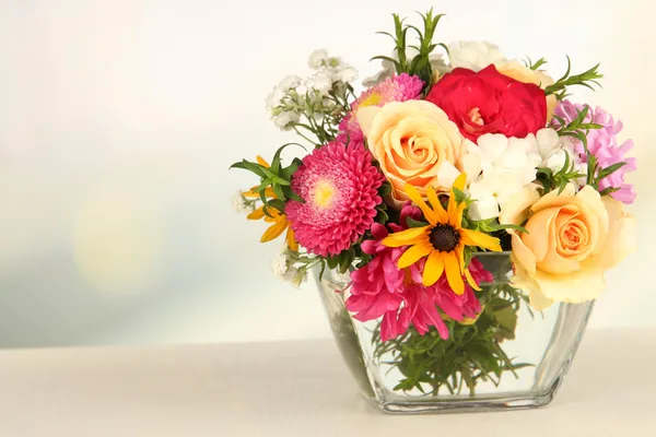 ガラスの花瓶、木製のテーブル, 明るい背景上に明るい花の美しい花束 — ストック写真