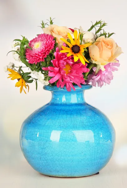 Belo buquê de flores brilhantes em vaso de cor, na mesa de madeira, no fundo brilhante — Fotografia de Stock